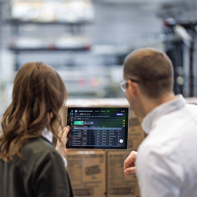 Two team members looking at a tablet in a plant