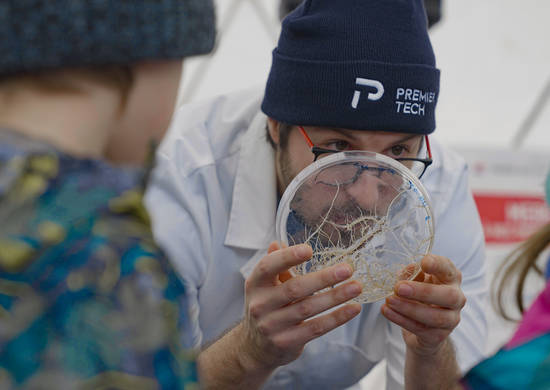 Équipier Premier Tech qui montre des racines de plante à des enfants